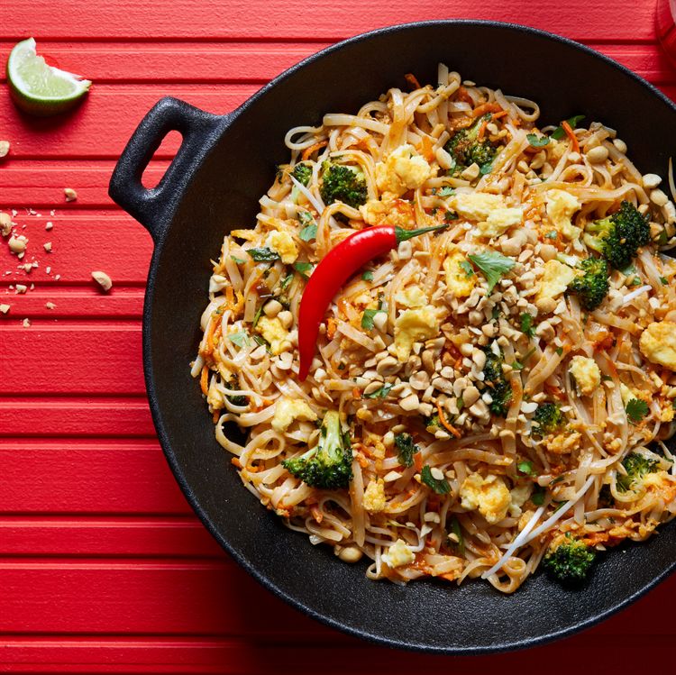 pad thai in a skillet with a chili pepper garnish