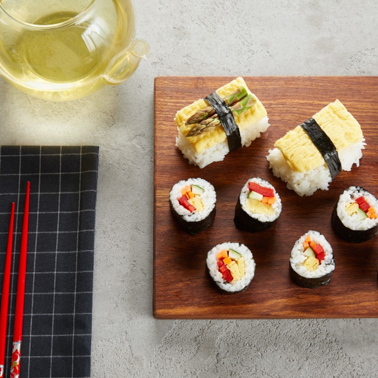 sushi on a serving board with chopsticks and tea